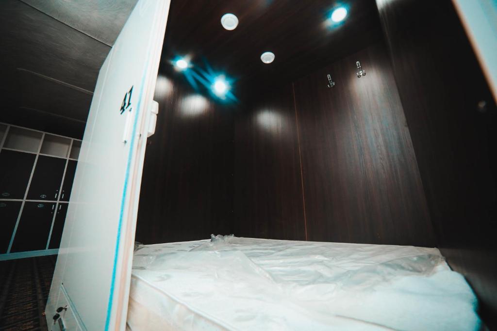 比什凯克Capsule hotel TechnoCave的冲浪板坐在房间床边