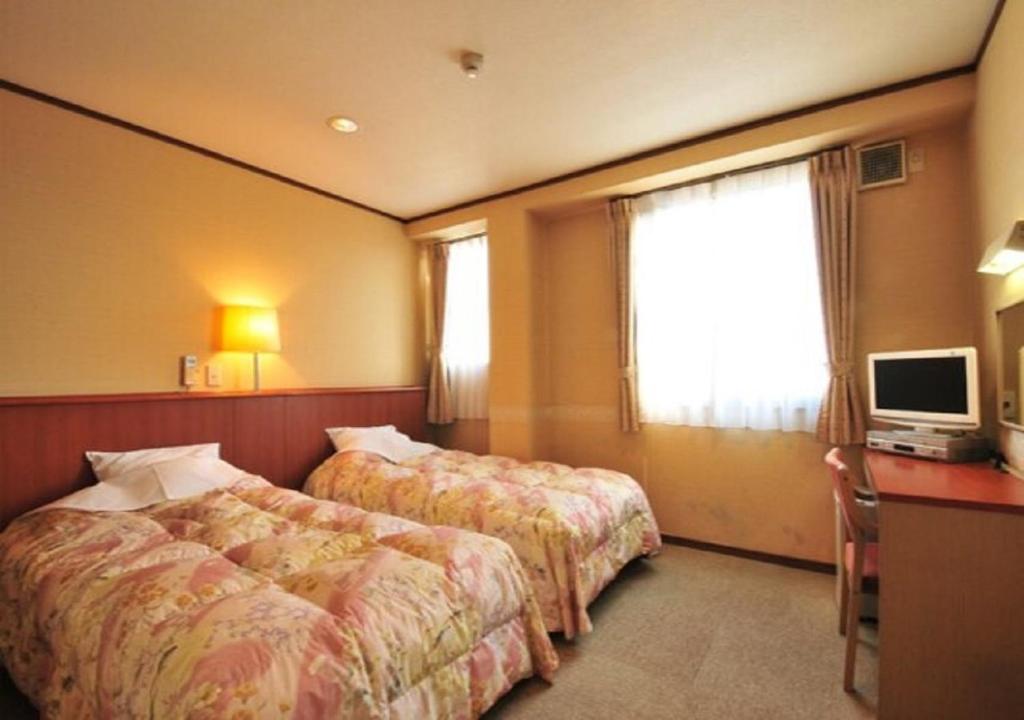 大村市Omura - Hotel / Vacation STAY 46226的酒店客房设有两张床、一张桌子和一台电视。