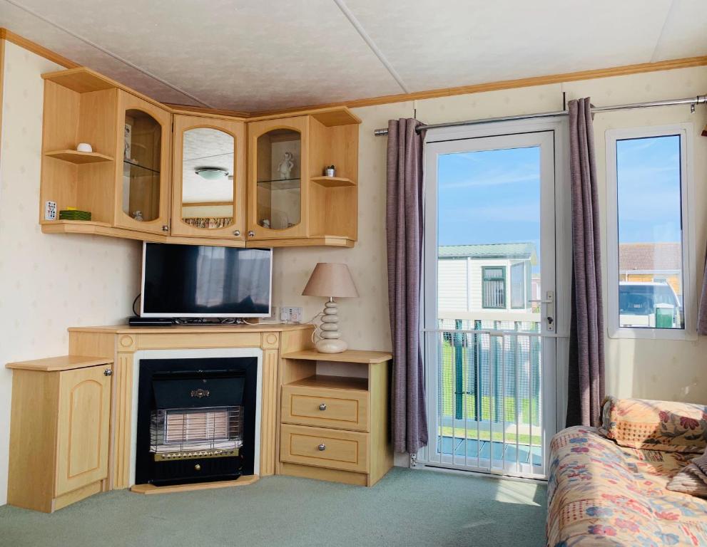 英戈尔德梅尔斯Golden Sands Caravan Hire Ingoldmells- FREE in caravan wifi- Access included to the on site club house, sports bar, arcade, coffee shop We have beach access, a fishing lake and a laundrette的一间带电视和壁炉的客厅