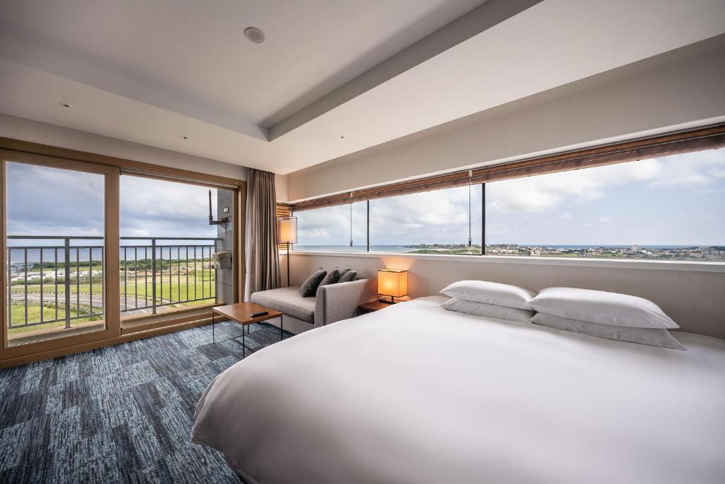 西归浦市Golden Tulip Jeju Seongsan Hotel的一间卧室设有一张大床和大窗户