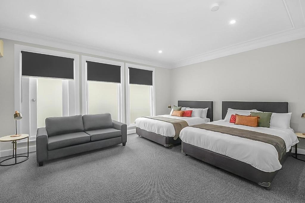 悉尼Horse and Jockey Hotel Homebush的酒店客房,配有两张床和椅子