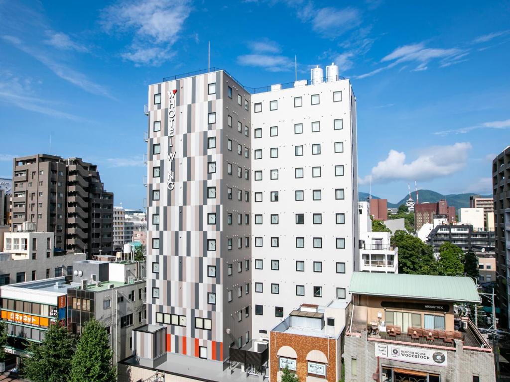熊本Hotel Wing International Select Kumamoto的一座高大的白色建筑,有建筑