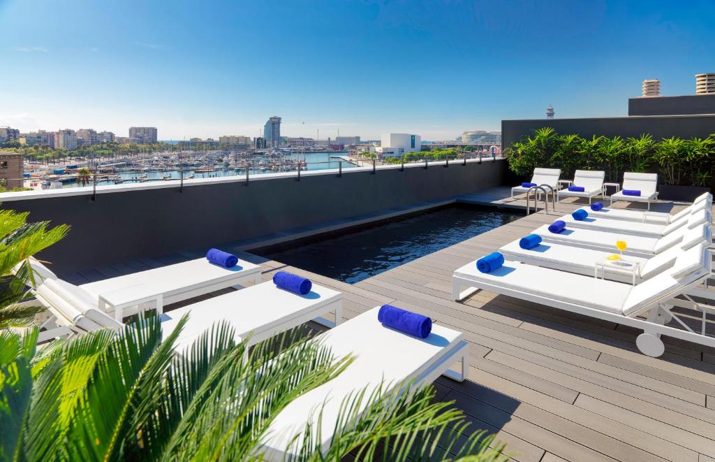 巴塞罗那H10贝尔港4 *索普酒店的一个带白色躺椅和游泳池的屋顶甲板