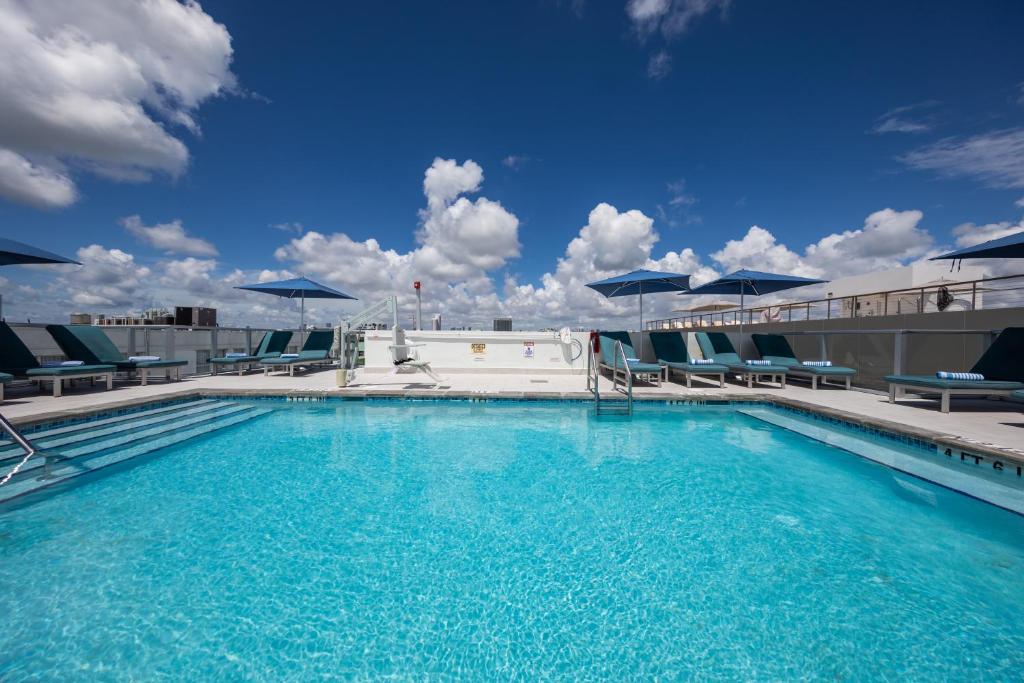 迈阿密海滩总统别墅酒店的大楼内带椅子和遮阳伞的大型游泳池