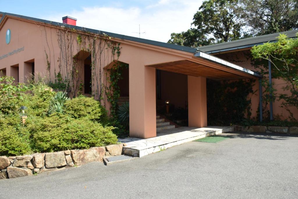 土庄町Taiyou no Ouchi的粉红色的建筑,带有门廊和灌木
