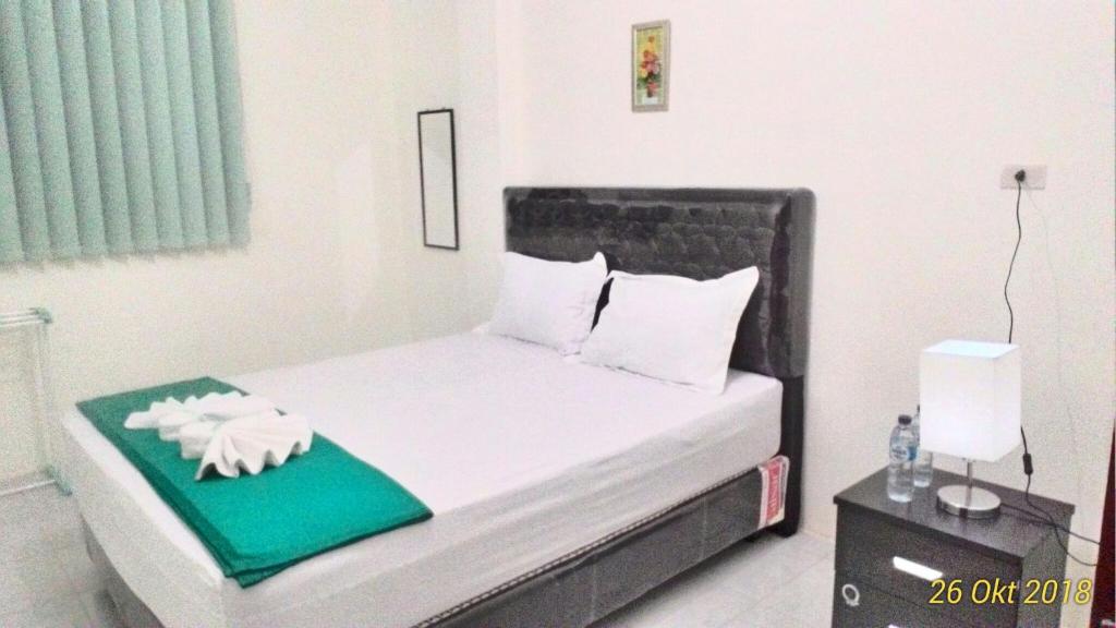 巴利盖Balige J&J Guest House 2的小卧室配有一张带绿色枕头的床和一张四柱床