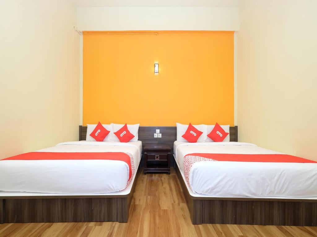 金马仑高原OYO 44029 Tudor Home Inn的配有红色和白色枕头的客房内的两张床