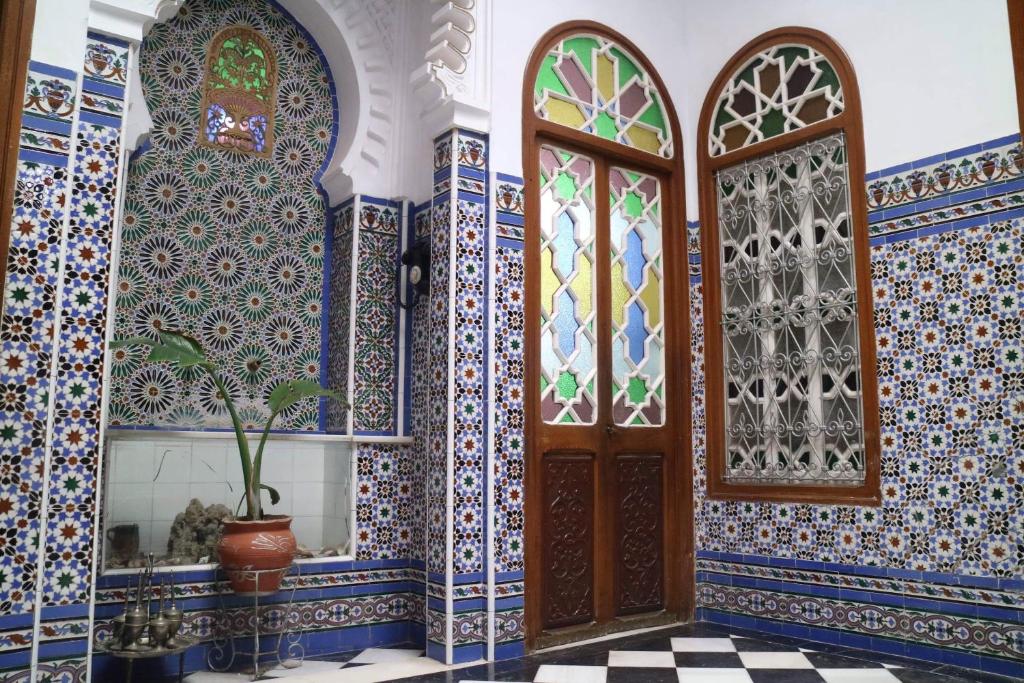 得土安Riad Soul of Tetouan的一间铺有蓝色和白色瓷砖的客房,设有木门