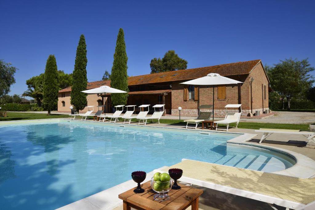 格罗塞托凡托利亚圣洛伦索酒店的房屋前的游泳池配有椅子和遮阳伞