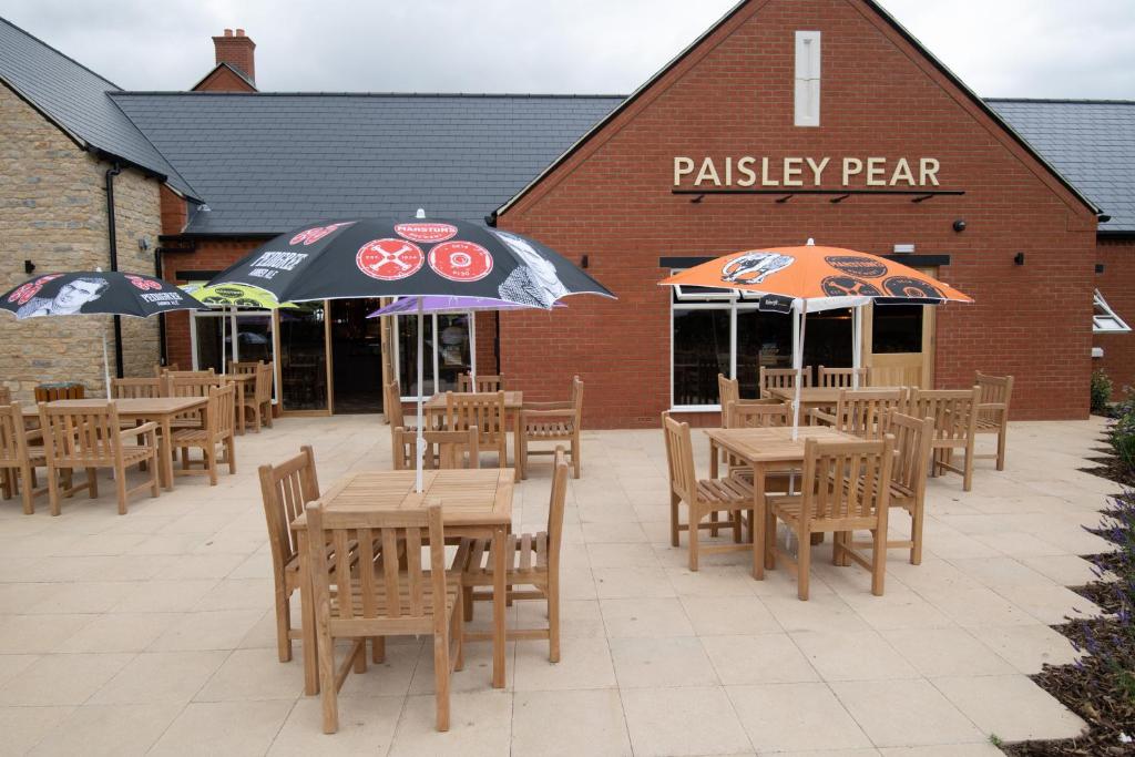 布拉克利Paisley Pear, Brackley by Marston's Inns的餐厅前方设有带桌子和遮阳伞的庭院。