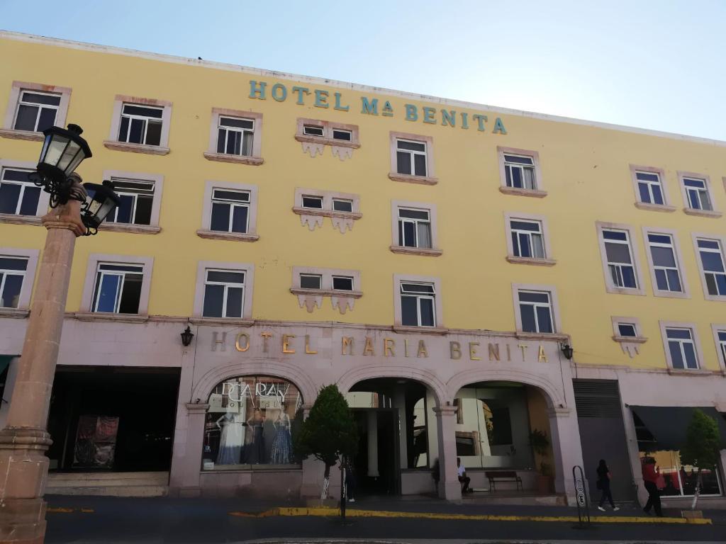 萨卡特卡斯Hotel Maria Benita的一座黄色的大建筑,上面写着我贝利亚的字眼