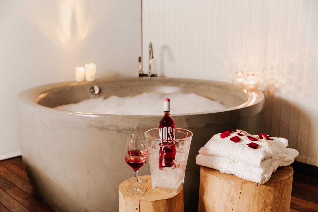 坎塔卢普斯El Recer de Masia Serra的浴缸配有一瓶葡萄酒和一杯葡萄酒
