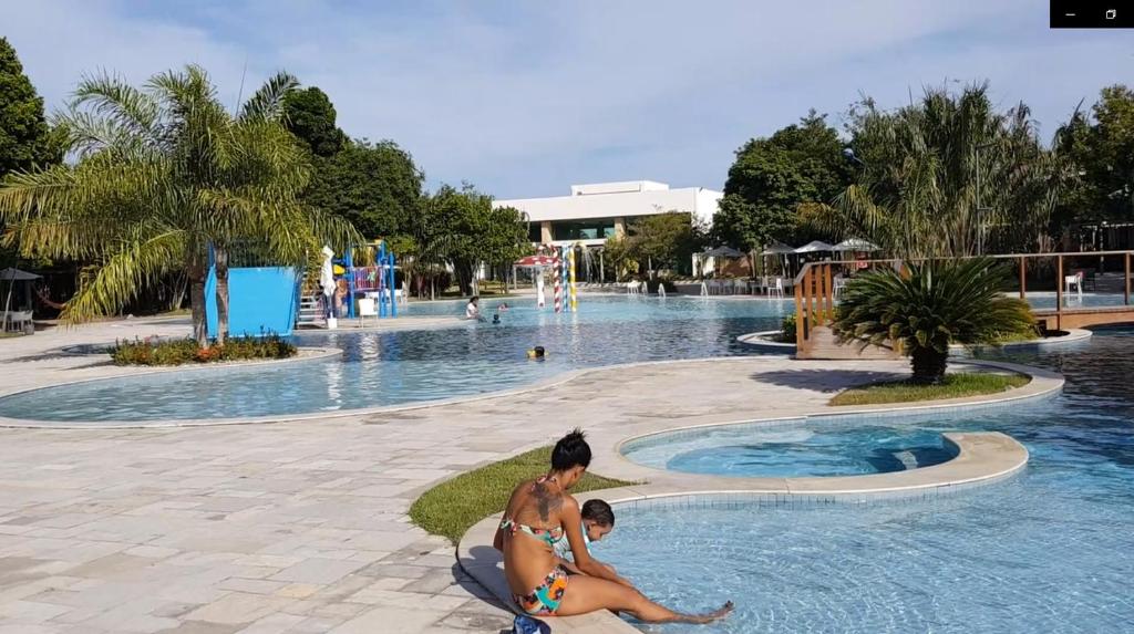 拉巴拉德纳圣米格尔Iloa Residence Resort - Barra de São Miguel的坐在游泳池前的男人和孩子