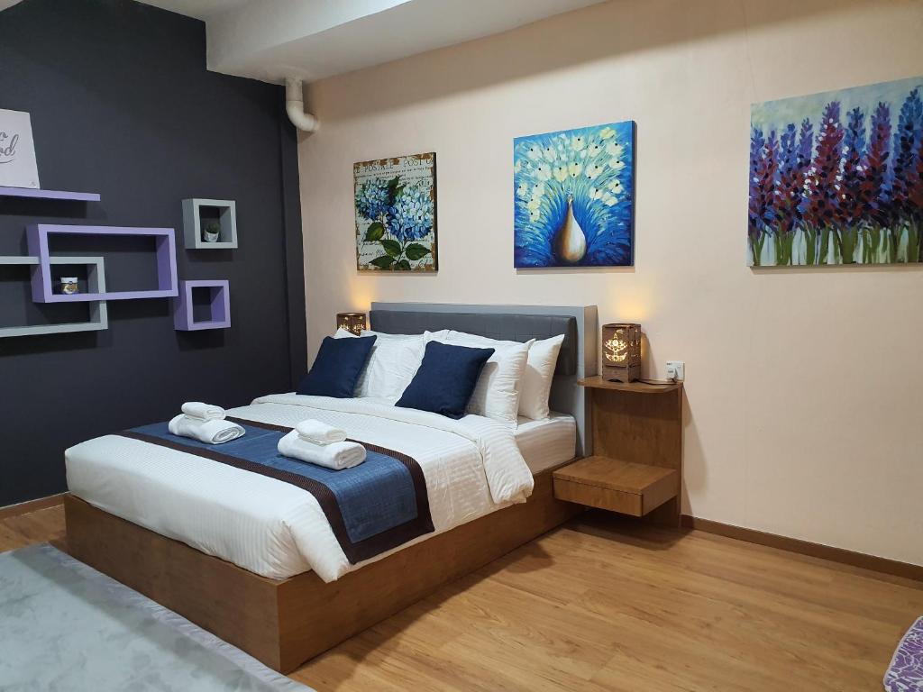 哥打巴鲁Assalam Hotel的卧室配有一张床,墙上挂有绘画作品
