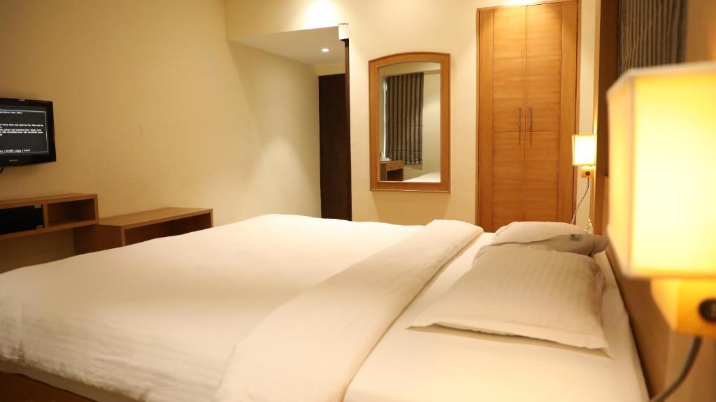 钦奈芒特庄园的一张白色的床,位于酒店带镜子的房间内