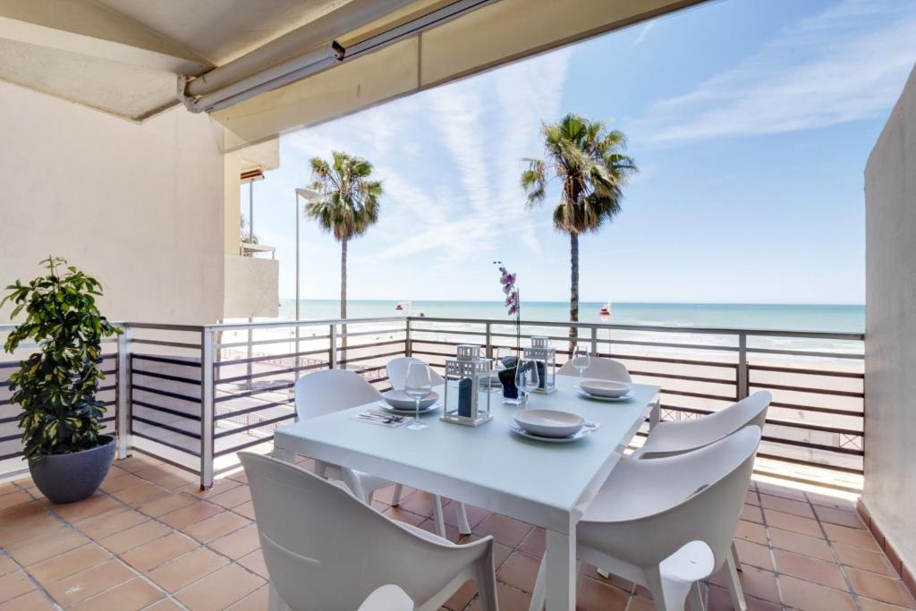 加的斯Apartamento La Terraza del Mar的海滩阳台的白色餐桌和椅子