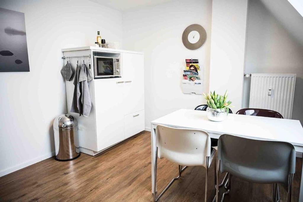 梅舍德FeWo Waldblick的厨房配有白色的桌椅和冰箱。