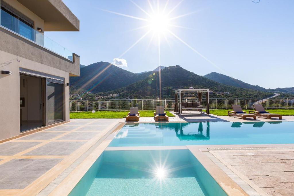 巴利恩Oraia Eleni Villa, infinite coastal views, By ThinkVilla的一个带椅子的游泳池,背景是山脉