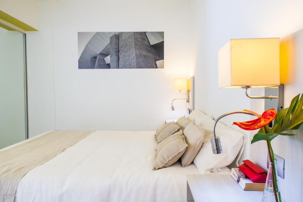 美洲海滩Udalla Park - Hotel & Apartamentos的白色的卧室配有床和一张带花卉的桌子