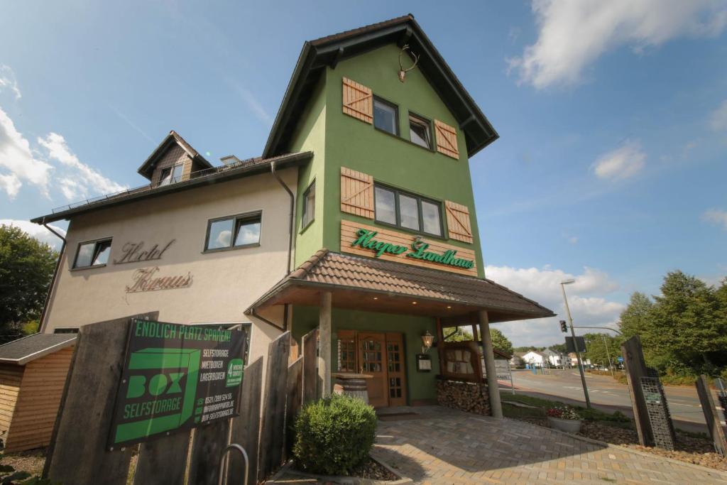 比勒费尔德Hotel Kraus/Heeper Landhaus的一座绿色和白色的建筑,设有商店