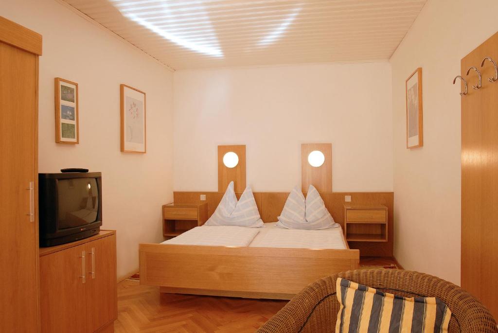 梅尔克梅尔克市中心马达尔酒店的一间卧室配有一张带白色枕头的床和一台电视。