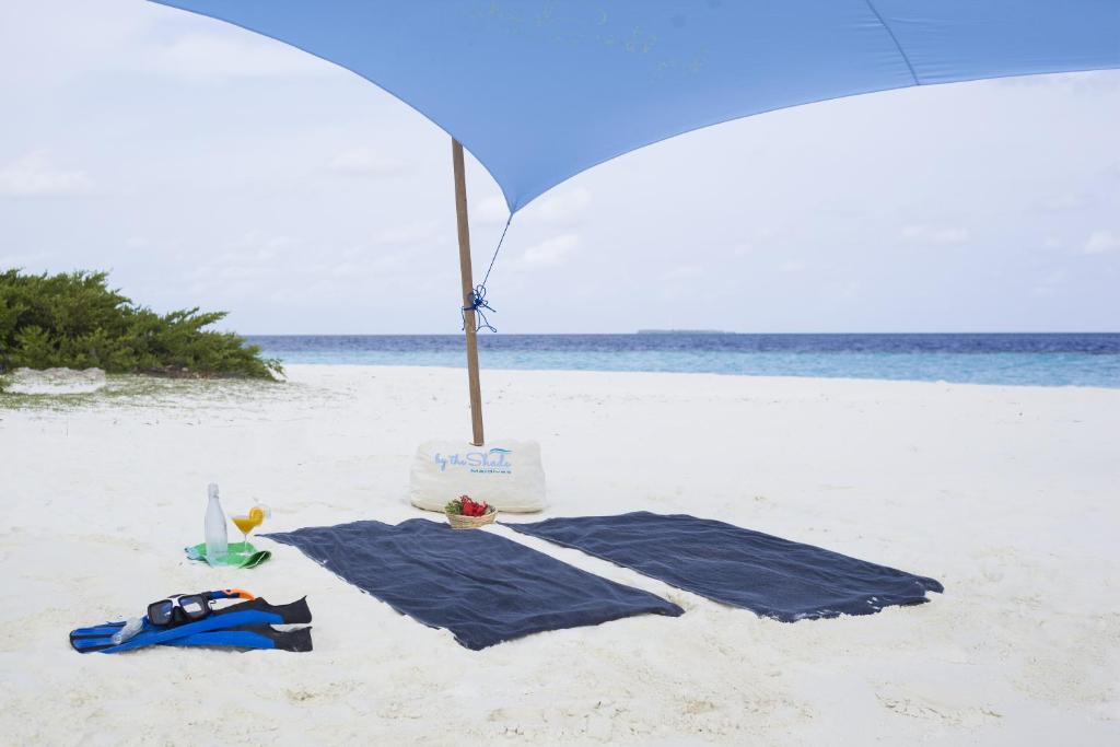 汉纳梅杜岛BY THE SHADE的沙滩上的蓝毛巾和遮阳伞