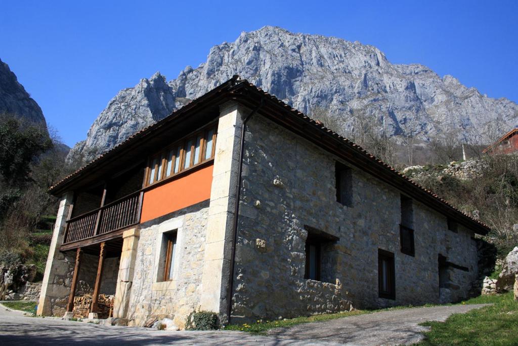 TaranesHotel Rural Llerau的一座以山为背景的石头建筑