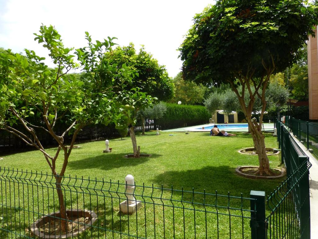 塞维利亚Milenium Palace - Garaje incluido - Piscina-FIBES的庭院前的围栏,有树木和游泳池