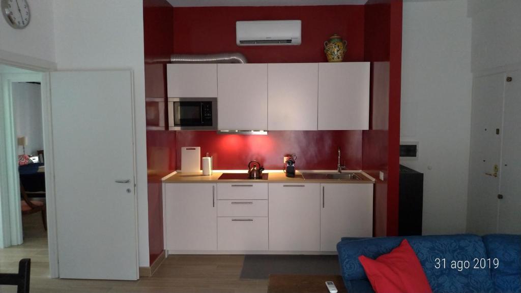 罗马Casa di Rosita的厨房配有白色橱柜和红色墙壁