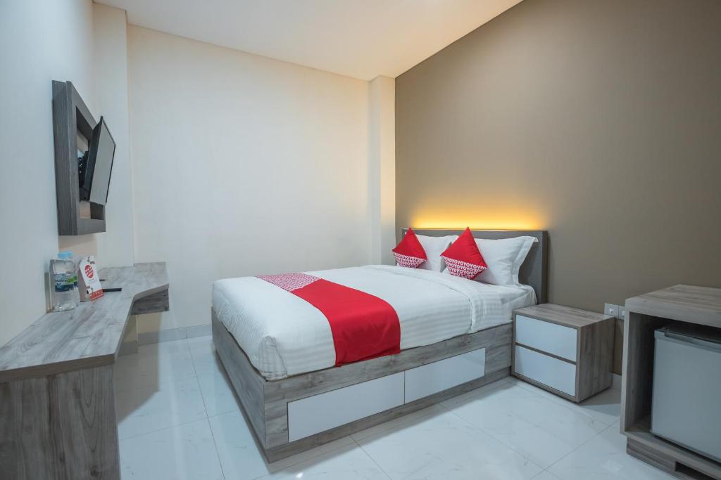雅加达OYO 1487 Residence Khoe的一间卧室配有一张带红色枕头的床和一台电视。