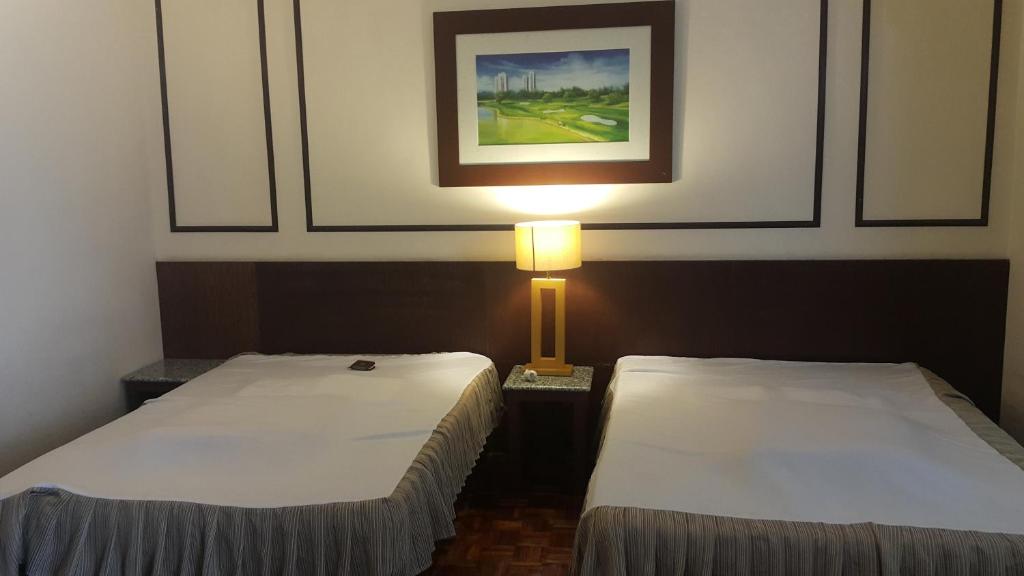 Kampong Pulau SebangCondo DSavoy Afarmosa的两张床位于带灯的房间。