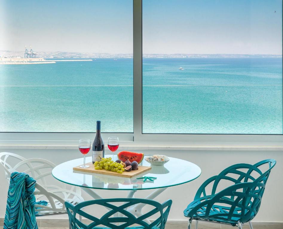 拉纳卡Luxury Penthouse 1BR-Seafront-Seasonal Pool-Central的一张桌子,上面放着两杯葡萄酒和一盘水果