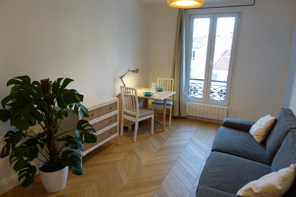 巴黎Sunny and quiet apartment的客厅配有蓝色的沙发和桌子