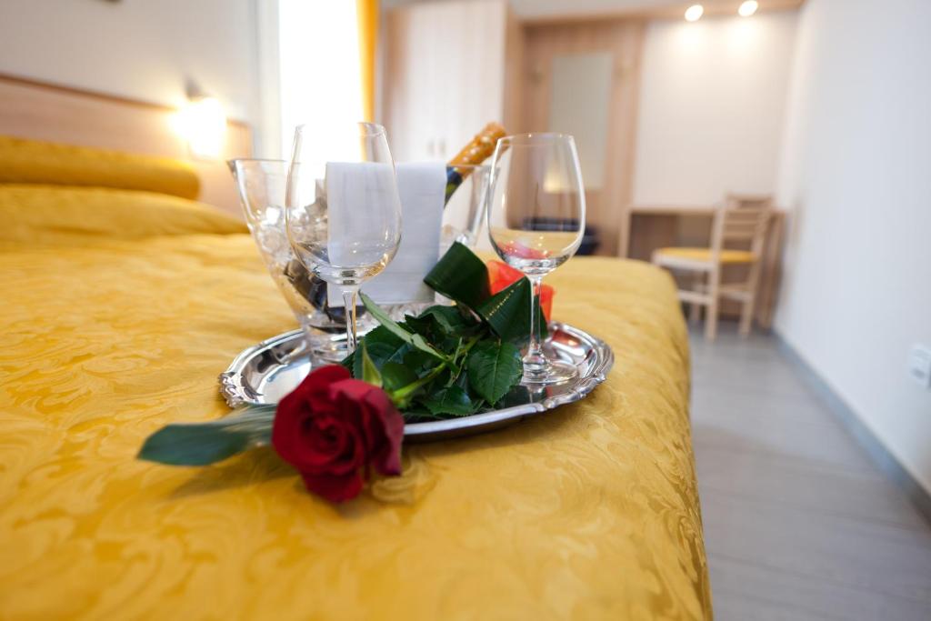 Fratta PolesineMotel Karibe的床上的托盘,上面放着两杯酒和玫瑰