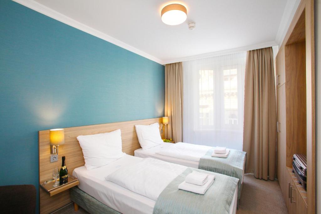 布达佩斯Medos Hotel的两张位于酒店客房的床,拥有蓝色的墙壁