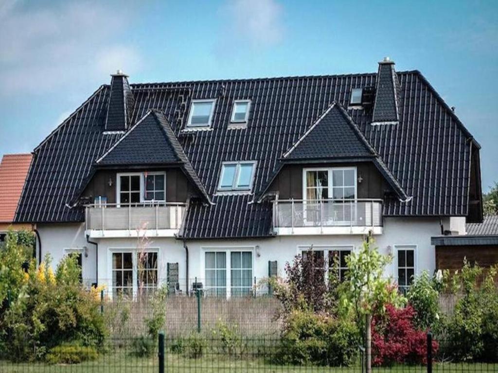 岑平FeWohnung Nele am Meer in Zempin的黑色屋顶的大型白色房屋