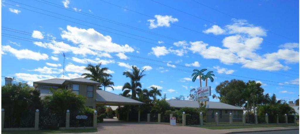 Biloela比洛拉棕榈汽车旅馆的一座棕榈树的建筑,一片蓝天,云朵