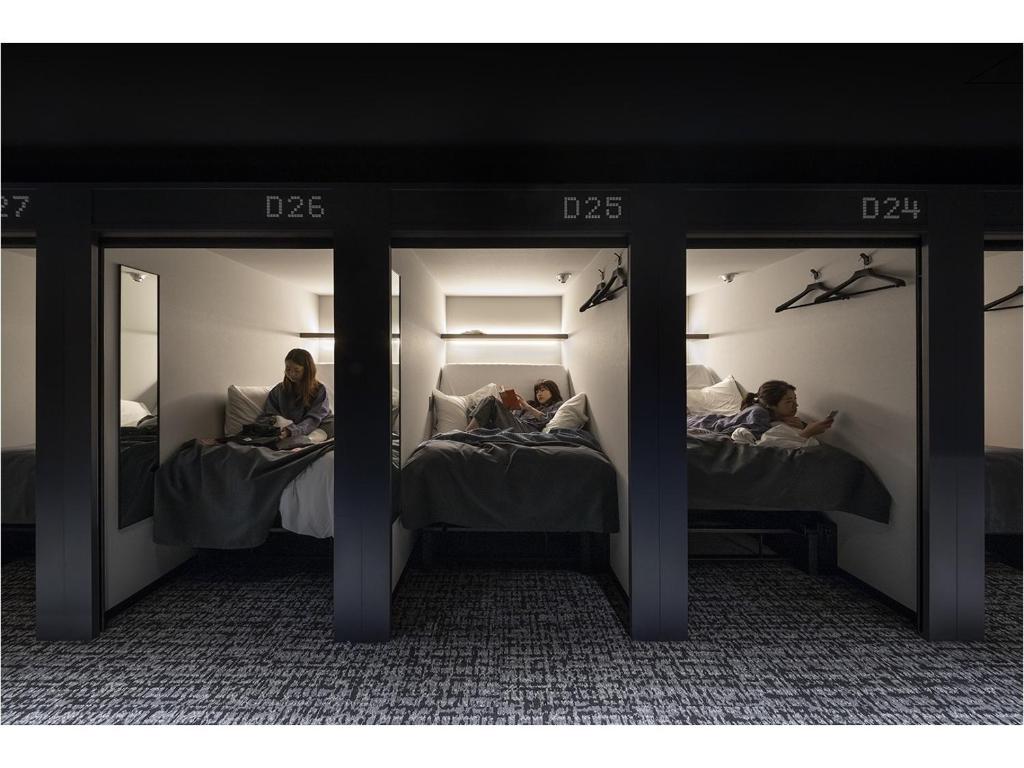福冈The Millennials Fukuoka的两人躺在带镜子的房间的床上