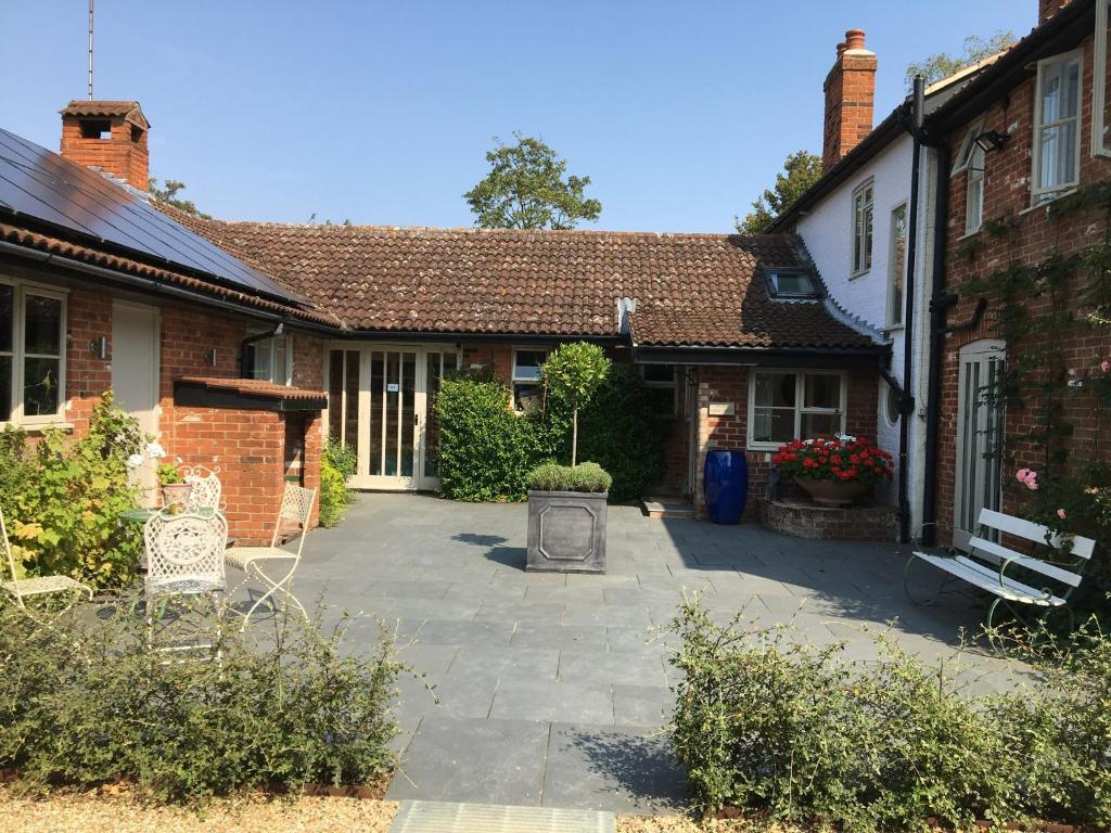 伍德布里奇Snipe Vineyard Cottage的房屋的庭院,前面设有长凳