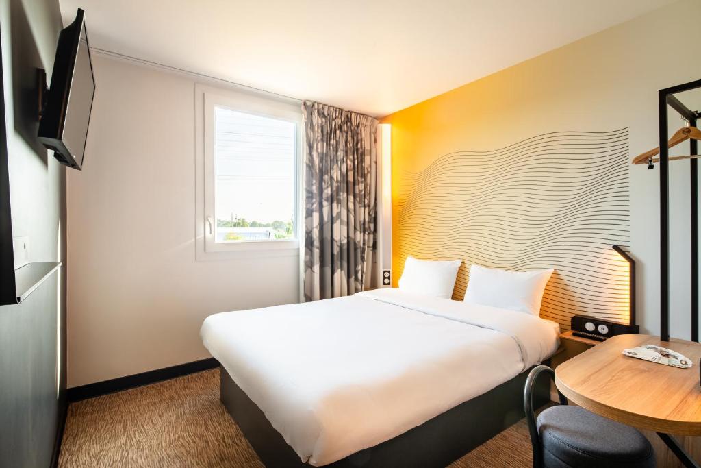 伊尼B&B HOTEL Igny Palaiseau的酒店客房设有一张大床和一张桌子。