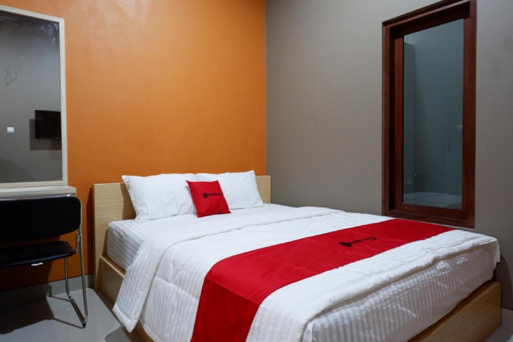 直葛RedDoorz Syariah near Stasiun Tegal的一间卧室配有一张带红色毯子的大床