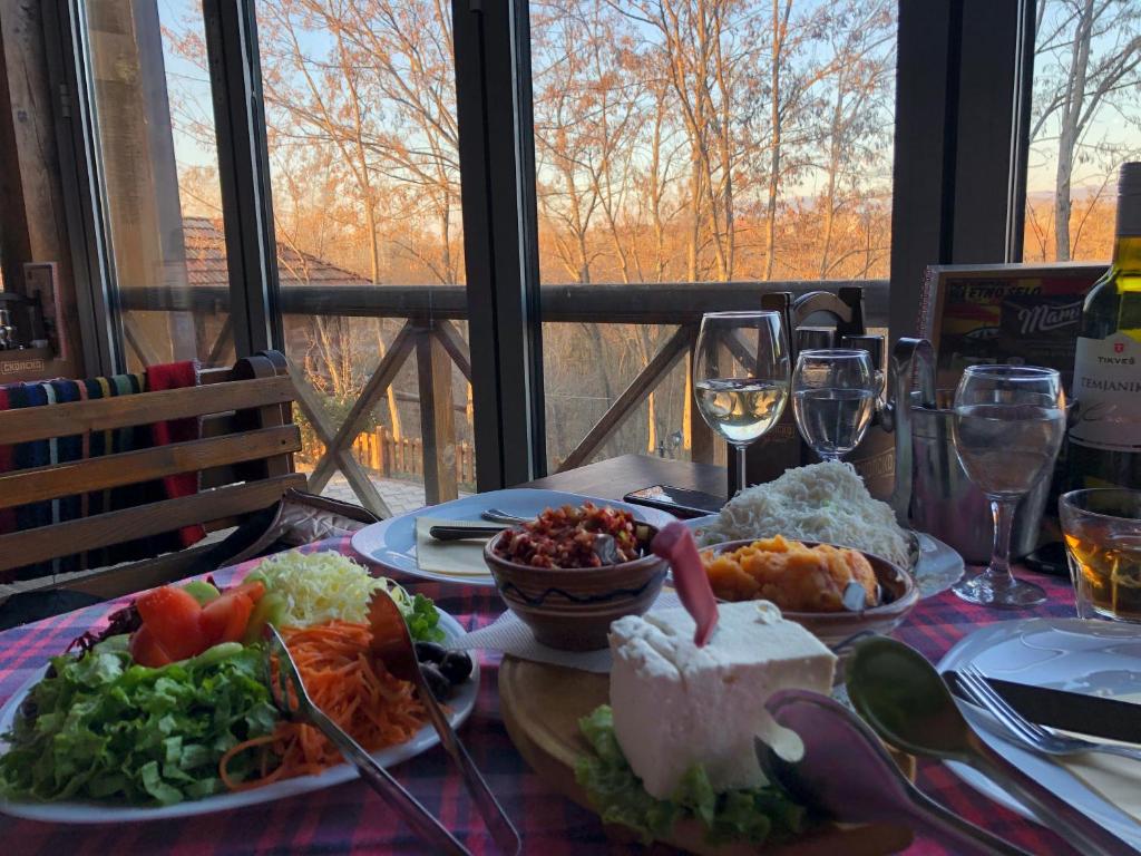 库马诺沃Hotel Etno Selo Timcevski的摆满食物和酒杯的桌子