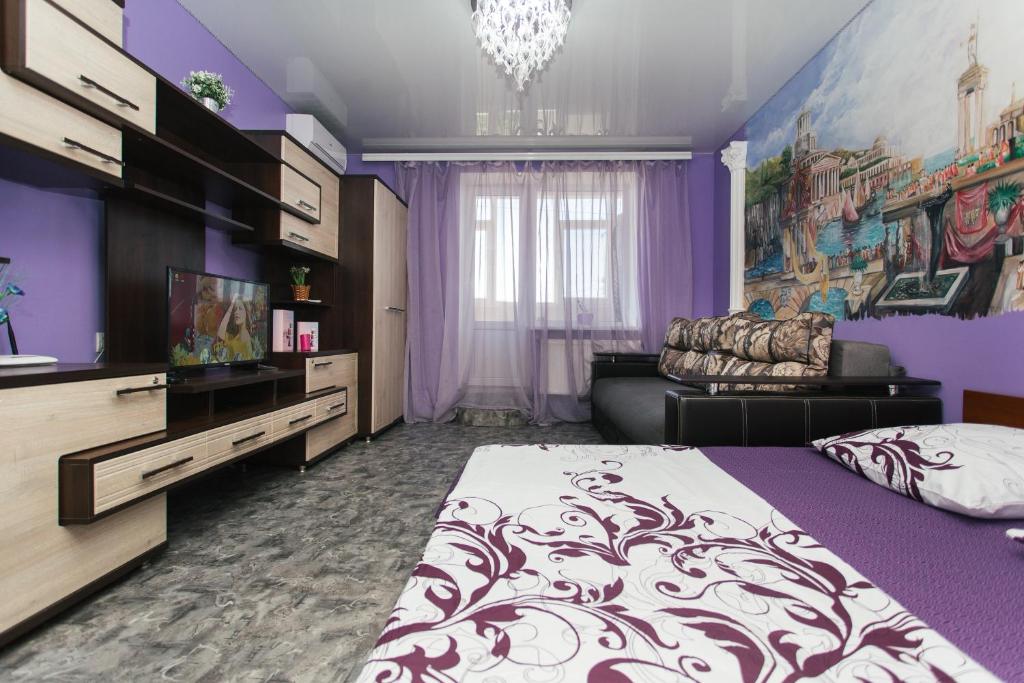 苏梅VIP Apartmens Faraon On Illinskaya 1 floor的紫色卧室配有一张床和一张沙发