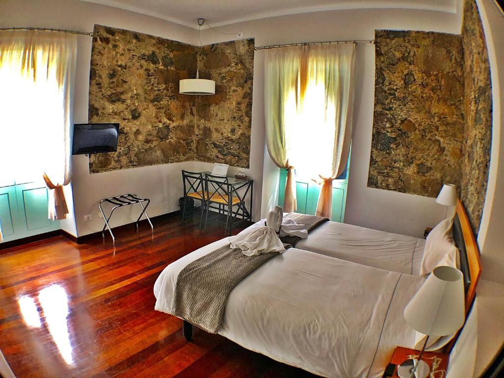 巴列埃尔莫索Hotel Rural Triana的一间卧室设有一张大床和两个窗户。