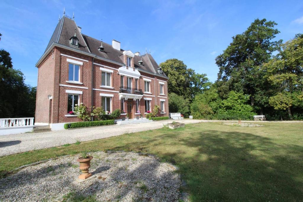 Mesnil-MartinsartBed & Breakfast au Château de Martinsart的一座带草地庭院的大型红砖房子