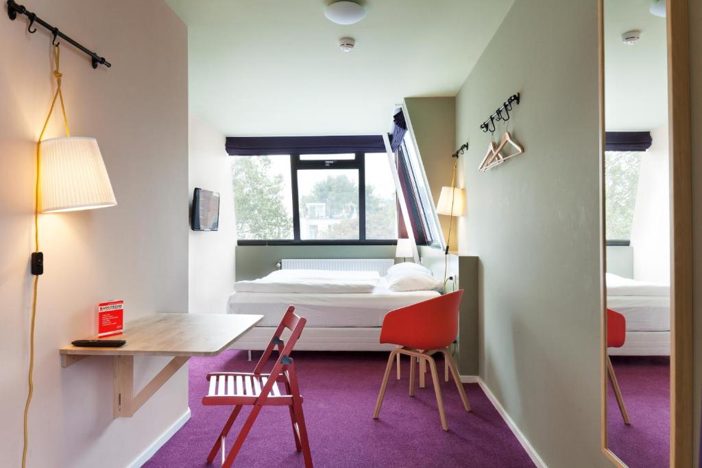 阿姆斯特丹尼勃曼果利亚酒店的客房设有一张床、一张桌子和椅子。