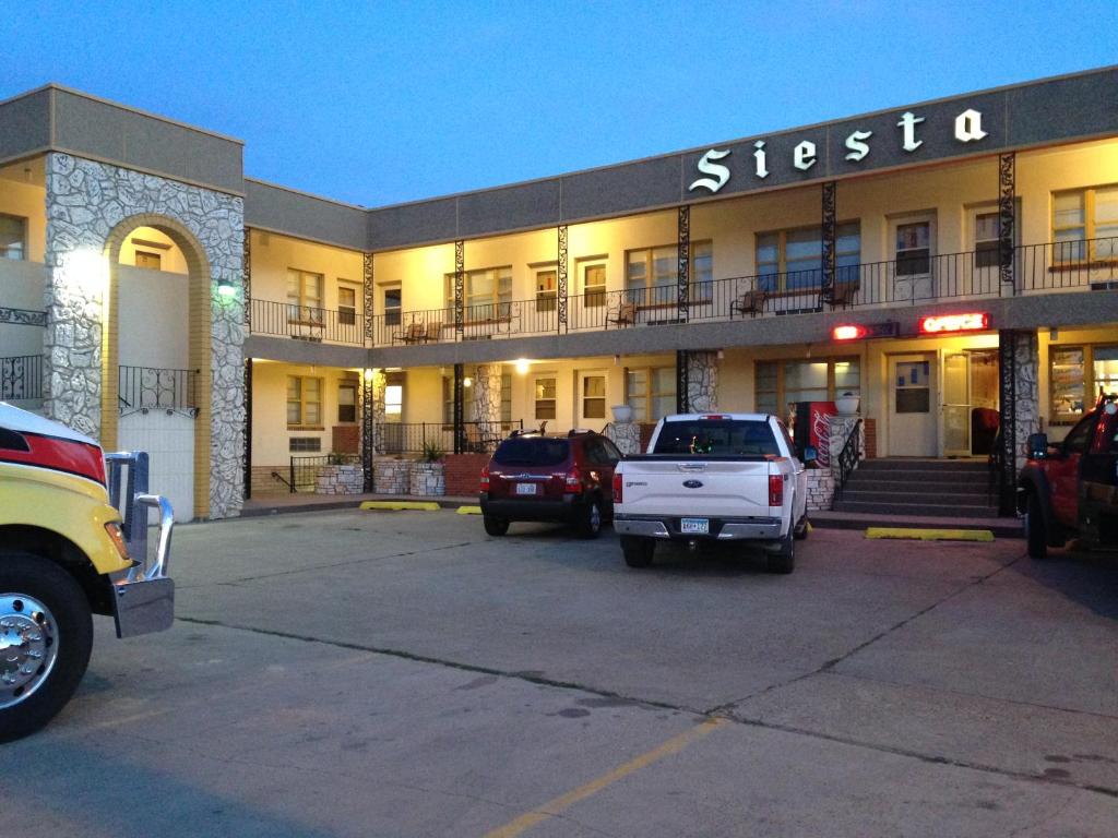 阿弗尔Siesta Motel的停车场内有车辆的建筑物