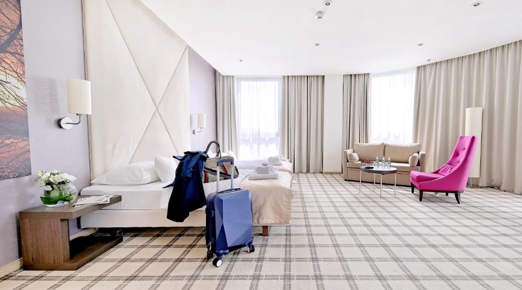 热舒夫热兹佐酒店的酒店客房,带一张床和行李箱