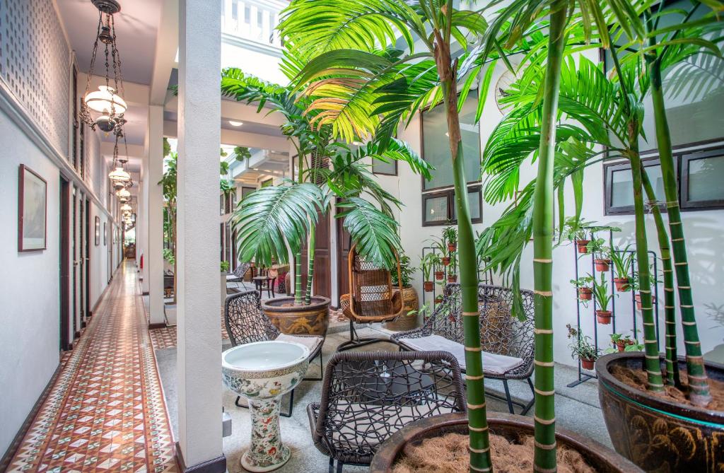 乔治市槟城槟榔酒店的建筑中带椅子和棕榈树的走廊