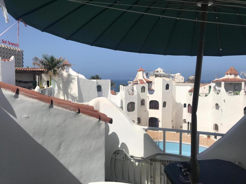 阿罗纳wonderful white appartament in las Tortugas的一座带游泳池的建筑顶部的绿色遮阳伞